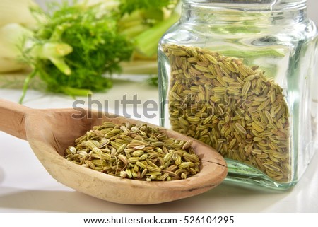 Fennel seeds in wooden spoon with glass vase close