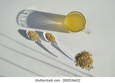 Fennel tea and fennel seeds on a white background, creativity and shadows in the composition. Aromatic and medicinal herbal tea concept. Top view, copy space.