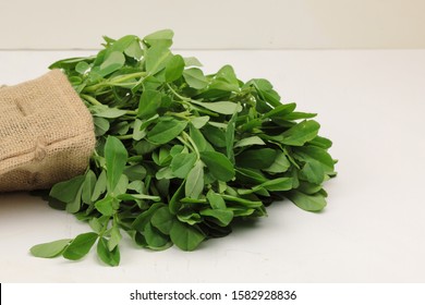 Fenugreek leavs or Methi leaves in a burlap bag on wooden background with copy space.