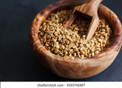 Fenugreek seeds in wooden bowl, spice, culinary ingredient, shamballa closeup  copy space