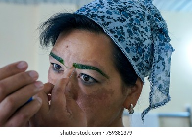 FERGANA, UZBEKISTAN – JULY 14, 2013 : Uzbek Woman Paint Traditional Unibrow With Homegrown Cosmetic.