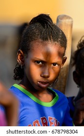 FERLO DESERT, SENEGAL - APR 25, 2017: Unidentified Fulani Little Girl With Braids In Colored Shirt Looks Ahead. Fulanis (Peul) Are The Largest Tribe In West African Savannahs