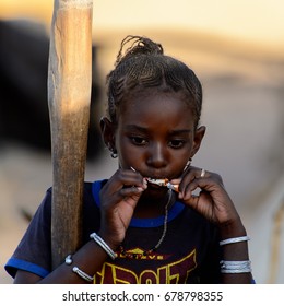 FERLO DESERT, SENEGAL - APR 25, 2017: Unidentified Fulani Little Girl With Braids Eats A Candy. Fulanis (Peul) Are The Largest Tribe In West African Savannahs