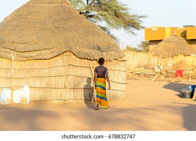 FERLO DESERT, SENEGAL - APR 25, 2017: Unidentified Fulani Woman In Colored Skirt Walks Near The Shack. Fulanis (Peul) Are The Largest Tribe In West African Savannahs