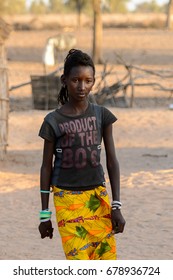 FERLO DESERT, SENEGAL - APR 25, 2017: Unidentified Fulani Girl With Braids Walks Along The Street. Fulanis (Peul) Are The Largest Tribe In West African Savannahs