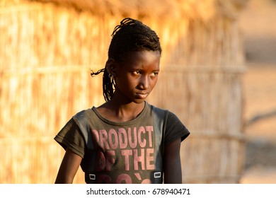 FERLO DESERT, SENEGAL - APR 25, 2017: Unidentified Fulani Girl With Braids Walks Along The Street. Fulanis (Peul) Are The Largest Tribe In West African Savannahs