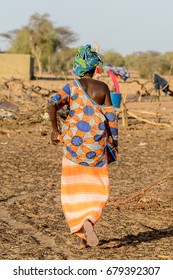 FERLO DESERT, SENEGAL - APR 25, 2017: Unidentified Fulani Woman In A Shirt With Opened Shoulder Walks Along The Street. Fulanis (Peul) Are The Largest Tribe In West African Savannahs