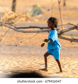 FERLO DESERT, SENEGAL - APR 25, 2017: Unidentified Fulani Little Girl In Blue Suit With Braids Walks Along The Street. Fulanis (Peul) Are The Largest Tribe In West African Savannahs