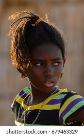 FERLO DESERT, SENEGAL - APR 25, 2017: Unidentified Fulani Girl With Braids In Colored Clothes Looks Away. Fulanis (Peul) Are The Largest Tribe In West African Savannahs