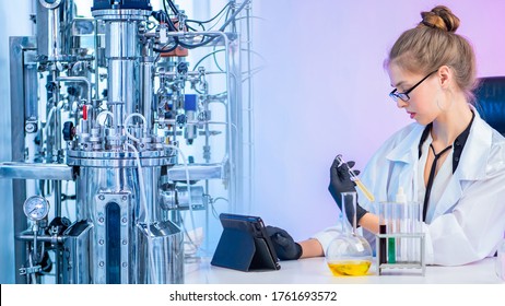 Fermentation Processes In The Laboratory. Laboratory Bioreactor And Chemist With Test Tubes And An Electronic Tablet. Development And Production Of Vaccines. Device For Microbiological Synthesis.