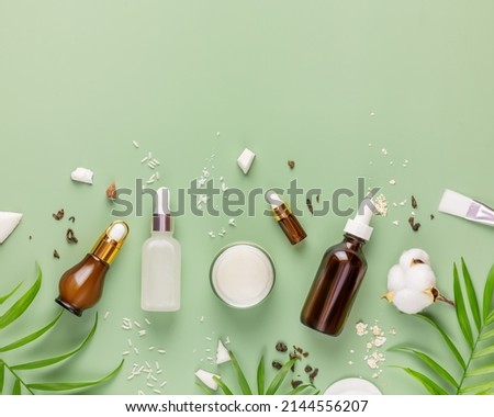 Fermented beauty care. Hande made rice serum, green tea serum, oatmeal cream and coconut water on a green background with copy space. Natural homemade cosmetics based on fermented products. Flat lay
