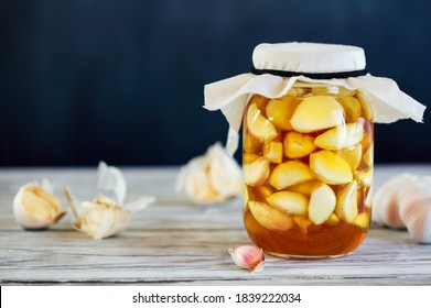 Fermented garlic cloves in a jar of honey, a rich source of probiotics, over a rustic wood background table. Selective focus with blurred background and foreground. - Powered by Shutterstock