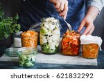Fermented preserved vegetarian food concept. Cabbage kimchi, broccoli marinated, sauerkraut sour glass jars over rustic kitchen table. Canned food concept.