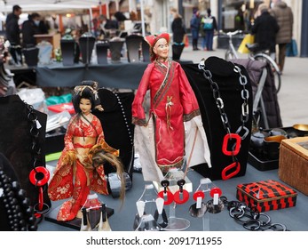 Ferrara, Italy - December 4, 2021. Flea Market, Stall Selling Costume Jewellery. There Are Asian Souvenir Dolls.