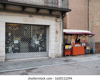 Ferrara, Italy - January 19, 2020. Chestnut Vendor Stall Next To A Lady Boutique. Strange Combination.