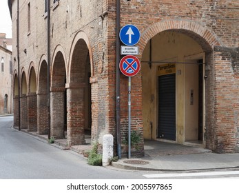 Ferrara, Italy - July 4, 2021. Ancient medieval colonnade in Via degli Spadari. You can see the portcullis of a hairdressing salon.