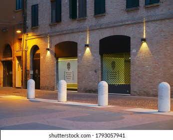 Ferrara, Italy - June 26, 2020. Pub with closed portcullis. Pedestrian street with cobblestones and bollards.