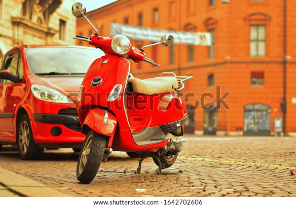 Ferrera / Italy - 24 January,2020: 2 different red\
means of transport. A scooter or motor scooter is a type of\
motorcycle with a step-through frame and a platform for the rider\'s\
feet.