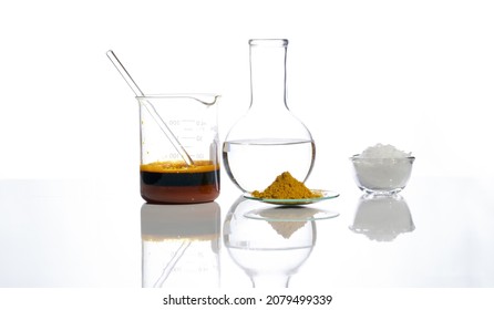 Ferric Chloride Liquid With Stirring Rod In Beaker, Crystal Clear Liquid In Flat Bottom Flask, Organic Curcuma Powder And White Flake Chemical. Closeup Chemical Ingredient On White Laboratory Table.