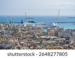 Ferries dock in the Port of Genoa behind a dense skyline of slate rooftops, historic domes, and cranes along the Ligurian coast under clear summer light