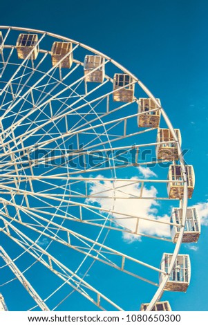 Ferris Wheel against blue cloudy sky on sunny weather