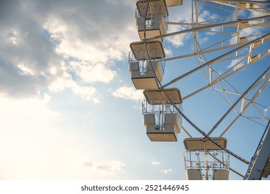 Ferris wheel against the sky with clouds, illuminated by the rays of the setting sun. Crikvenica, Croatia 