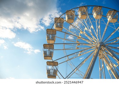 Ferris wheel against the sky with clouds, illuminated by the rays of the setting sun. Crikvenica, Croatia 