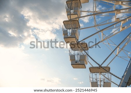 Ferris wheel against the sky with clouds, illuminated by the rays of the setting sun. Crikvenica, Croatia 