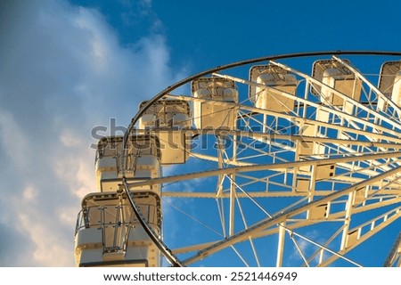 Ferris wheel against the sky with clouds, illuminated by the rays of the setting sun. Crikvenica, Croatia 