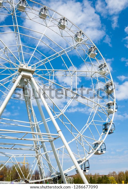 Ferris wheel an amusement-park or fairground ride\
consisting of a giant vertical revolving wheel with passenger cars\
suspended on its outer\
edge.