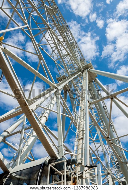 Ferris wheel an amusement-park or fairground ride\
consisting of a giant vertical revolving wheel with passenger cars\
suspended on its outer\
edge.