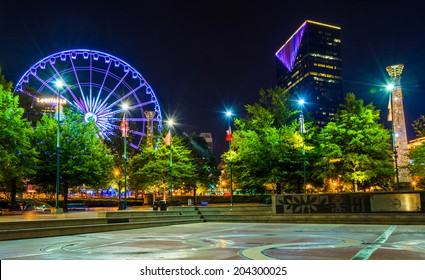 Ferris Wheel And Buildings Seen From Olympic Centennial Park At Night In Atlanta, Georgia.