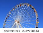 Ferris wheel featuring colourful seating pods against backdrop of blue sky