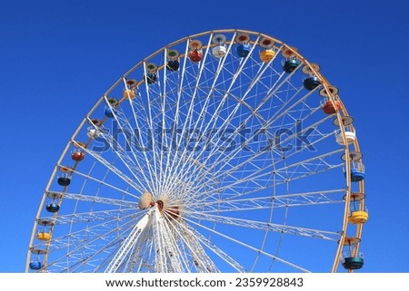 Ferris wheel featuring colourful seating pods against backdrop of blue sky
