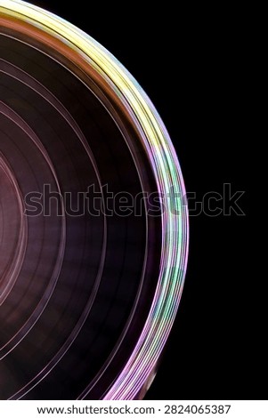 Ferris wheel lights creating light trails and motion blur against a dark sky