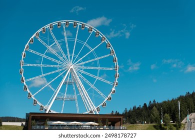 Ferris Wheel on Sunny Day. A Ferris wheel stands prominently against a clear blue sky on a sunny day. - Powered by Shutterstock