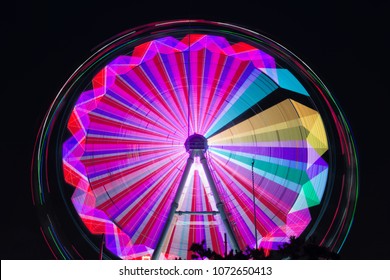 Ferris Wheel And Rollercoaster In Motion At Amusement Park At Night