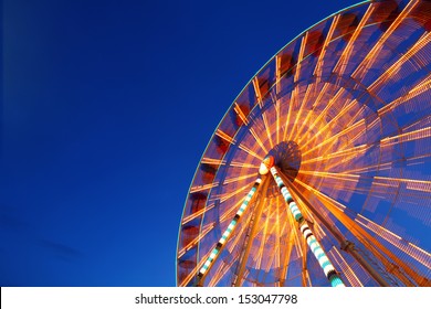 Ferris wheel and rollercoaster in motion at amusement park at night