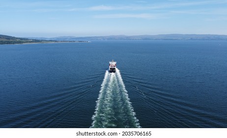 Ferry boat heading coming in from a distance on a clear sunny day. Beautiful blue sea with views of the Scottish hills in the distance.