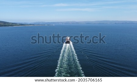 Ferry boat heading coming in from a distance on a clear sunny day. Beautiful blue sea with views of the Scottish hills in the distance.