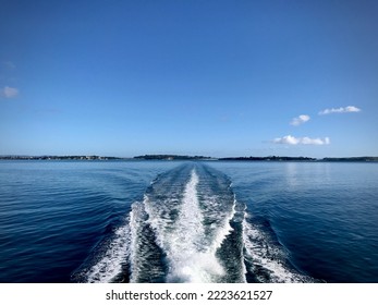 Ferry Creating A White Boat Wake Traveling Away From Land.