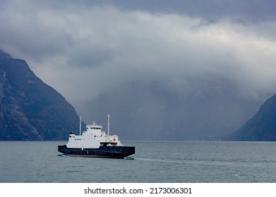 Ferry Crossing The Fjord In Norway. Dark Rainy Clouds In The Sky, Dark Misty Mountains, Dark Sea Water