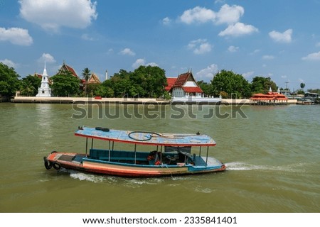Ferry wooden boat sailing on Chao Phraya river pass wat Klang Kret located opposite of Ko Kret, Nonthaburi, Thailand. Thai language red banner means Klang Kret temple.