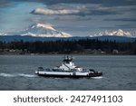 Ferryboat crossing Hale Pass from the mainland to Lummi Island, Washington. Snow covered Mt. Baker and the Three Sisters mountains, in the Cascade Range, can be seen in the background. 