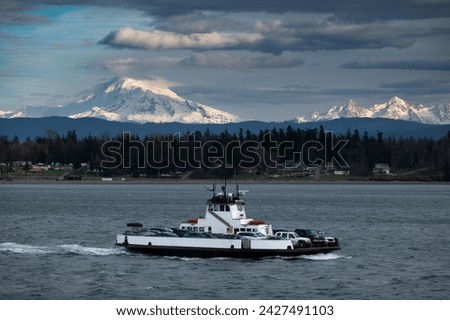 Ferryboat crossing Hale Pass from the mainland to Lummi Island, Washington. Snow covered Mt. Baker and the Three Sisters mountains, in the Cascade Range, can be seen in the background. 