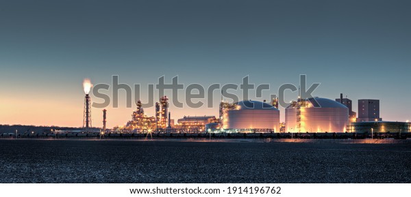 Fertilizer plant in an agricultural\
landscape at sunset. Railroad tanker cars stretched across the\
image. Night shot with lights on imposed on sunset\
background.