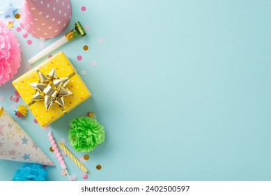 Festal gathering visualization. Top view shot capturing festive elements like candies, wrapped gift, birthday hats, party blower, candles, confetti on subtle sky blue background with space for text