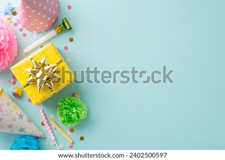 Festal gathering visualization. Top view shot capturing festive elements like candies, wrapped gift, birthday hats, party blower, candles, confetti on subtle sky blue background with space for text