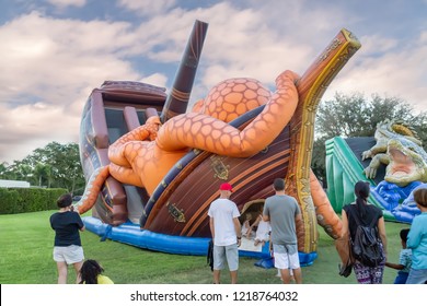 Festival Filled With A Much-themed Bounce House For Kids To Enjoy. Parents And Children Gather In Front Of The Large Community Bounce House Shaped Like An Octopus On Top Of An Old Ship.