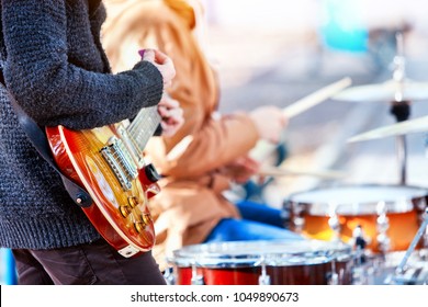 Festival music band. Hands playing on percussion instruments in city park. Drums with sticks closeup. Body part of male musicians. Sharpen is guitar and man hand. Hobby of adults. - Powered by Shutterstock